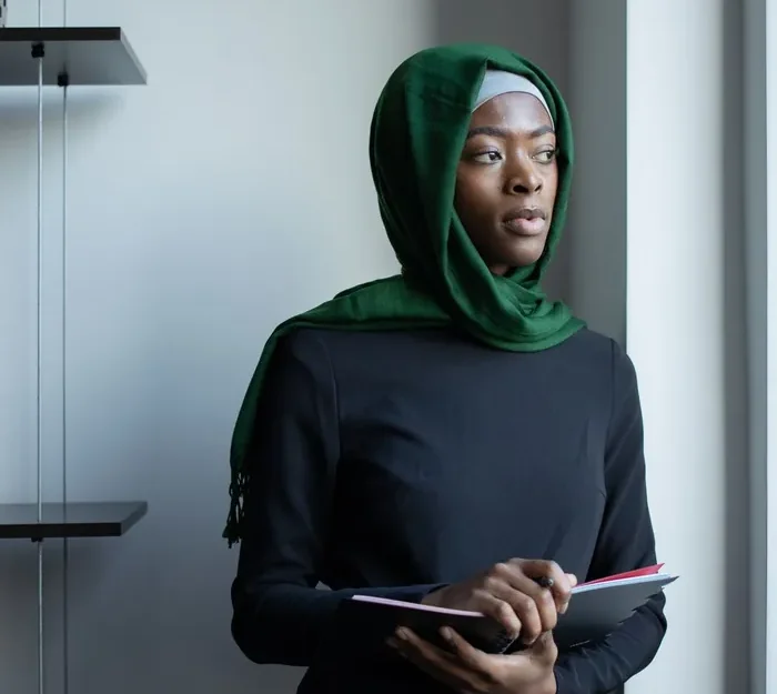 A female Quran teacher in a green hijab holding a tablet