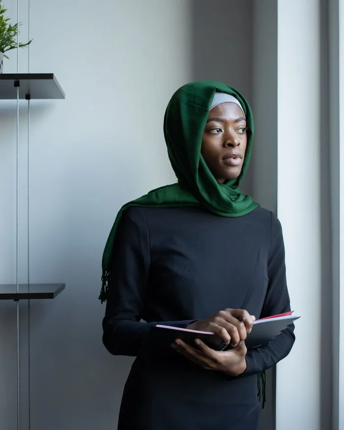 A female Quran teacher in a green hijab holding a tablet