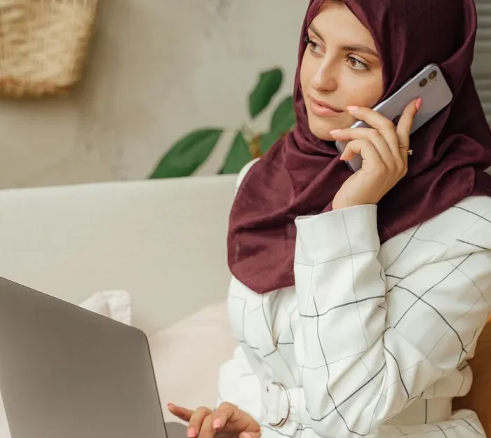 A female Quran teacher working at a laptop in a bright room