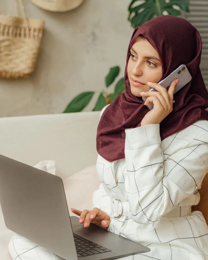 A female Quran teacher working at a laptop in a bright room